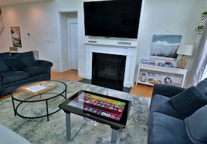 Una sala de estar con chimenea, un televisor de pantalla plana, una mesa de centro y dos sofás.