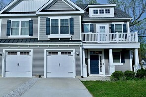 A two-story house with a front porch, two garage doors, and a balcony. - Coastal Club * 19117 Twin House w 4BR, 3.5 Baths, Sleeps 11 (Lewes)
