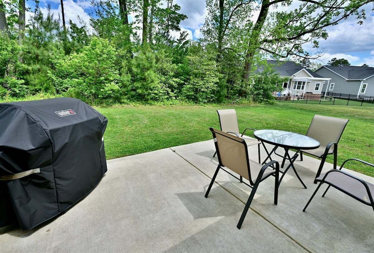 Un patio al aire libre con una parrilla, dos sillas y una mesa.