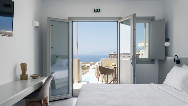 Une chambre d’hôtel avec un lit, un bureau, une chaise et une vue sur la mer.