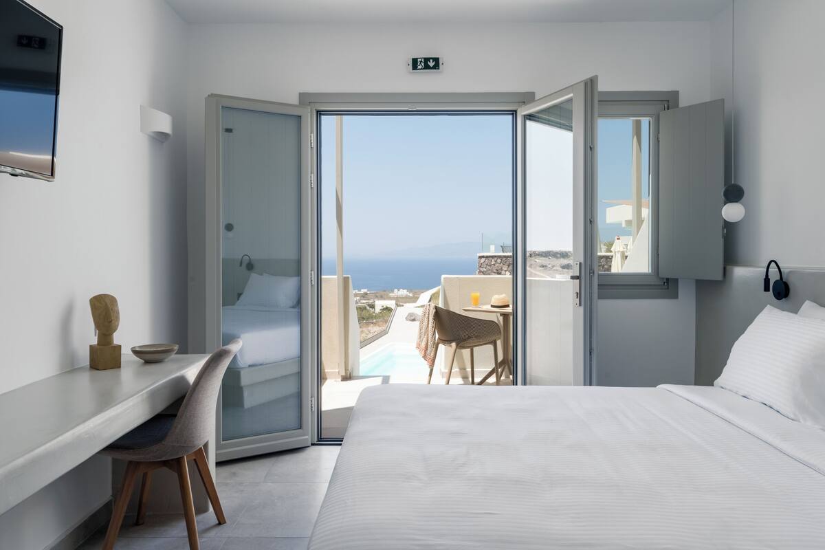 Ein Hotelzimmer mit Bett, Schreibtisch, Stuhl und Meerblick.