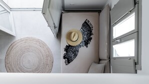Une petite pièce comprenant un lit, un chapeau accroché au mur et un tapis rond en fibres tressées.