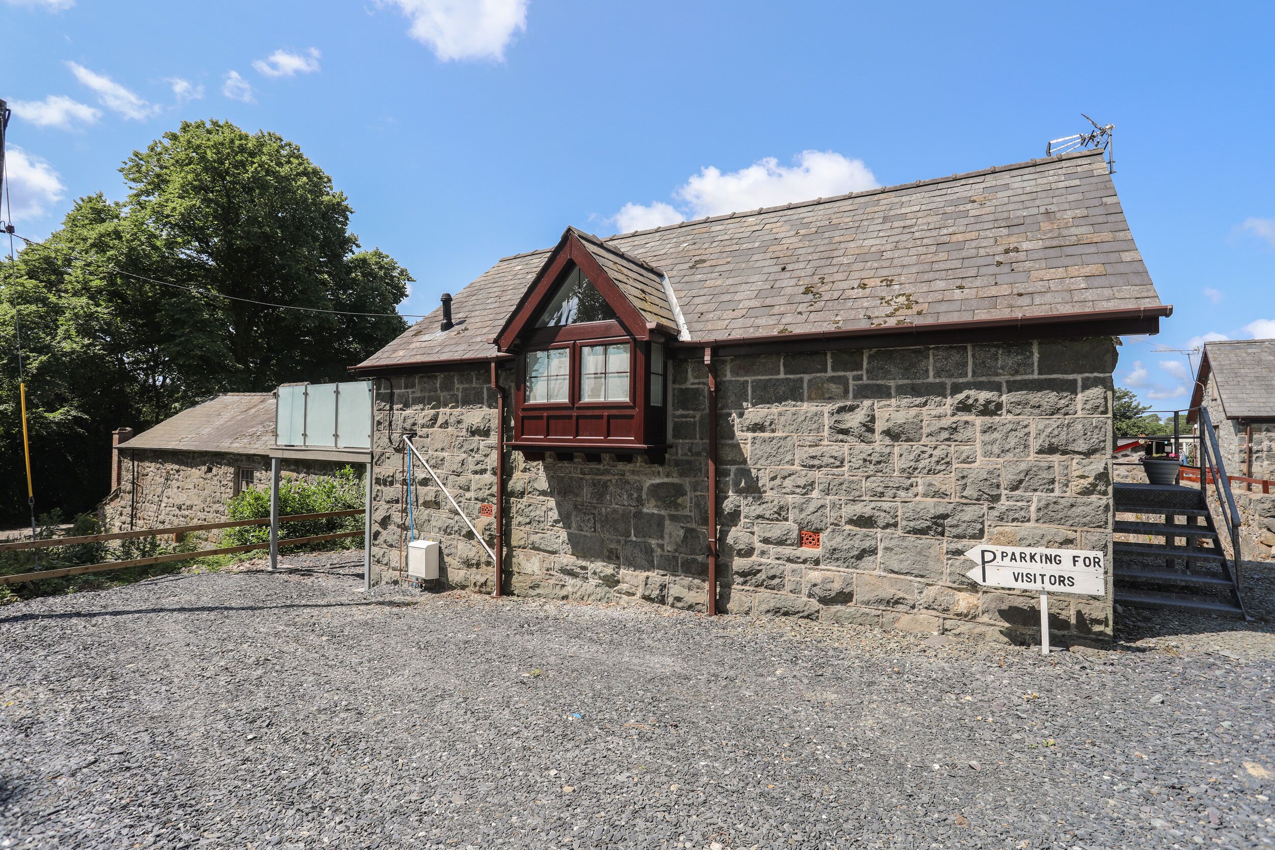 A stone building with a red window and a sign indicating parking for visitors.