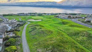 En golfbana med ett vattenhinder, omgiven av bostadshus och en väg.