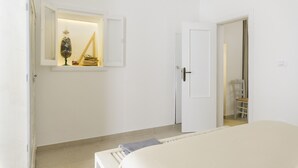 Un dormitorio minimalista con cama, armario y un espejo que refleja una escalera.