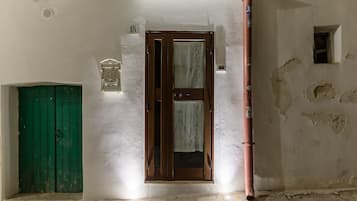 A hallway with a green door, a wooden door with a curtain, and a wall with a number sign.