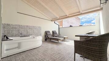 Relax in style with a bathtub and lounge chairs, set amidst a beautifully patterned space.