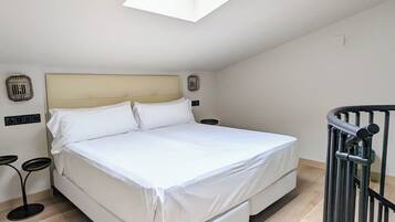 A bedroom with a bed, a skylight, a bedside table, and a chair.