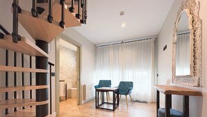 A modern hotel room with a wooden staircase, a dining area with two chairs, a large mirror, and a view of the outside through sheer curtains. - Akla Hotel Badajoz (Badajoz)