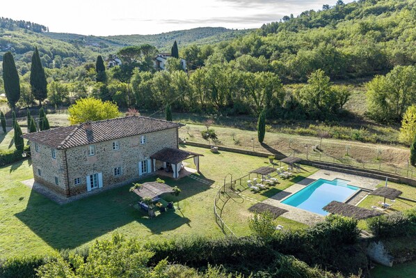 A stone house with a pool and outdoor seating.