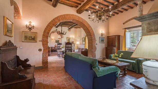 Una habitación tradicional con vigas de madera a la vista, chimenea de ladrillo y sofá azul.