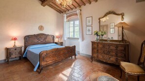 Un dormitorio con cama de madera, cómoda, silla, espejo y candelabro.