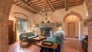 Una sala rústica con vigas de madera a la vista, una chimenea y una zona de estar acogedora.