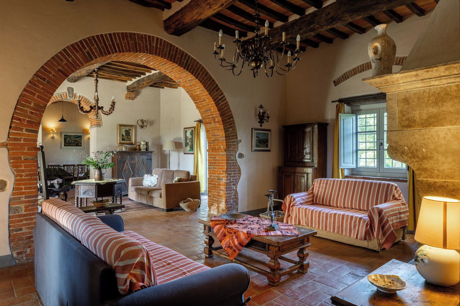 A cozy living room with a fireplace, a dining area, and a kitchen visible through an archway.