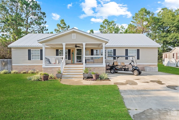 A single-story house with a porch, a covered front entrance, and a small patio area.