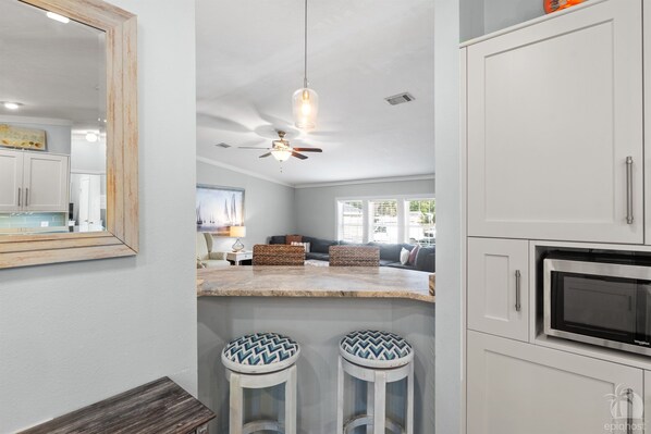 A kitchen with a bar area, a ceiling fan, and a microwave.