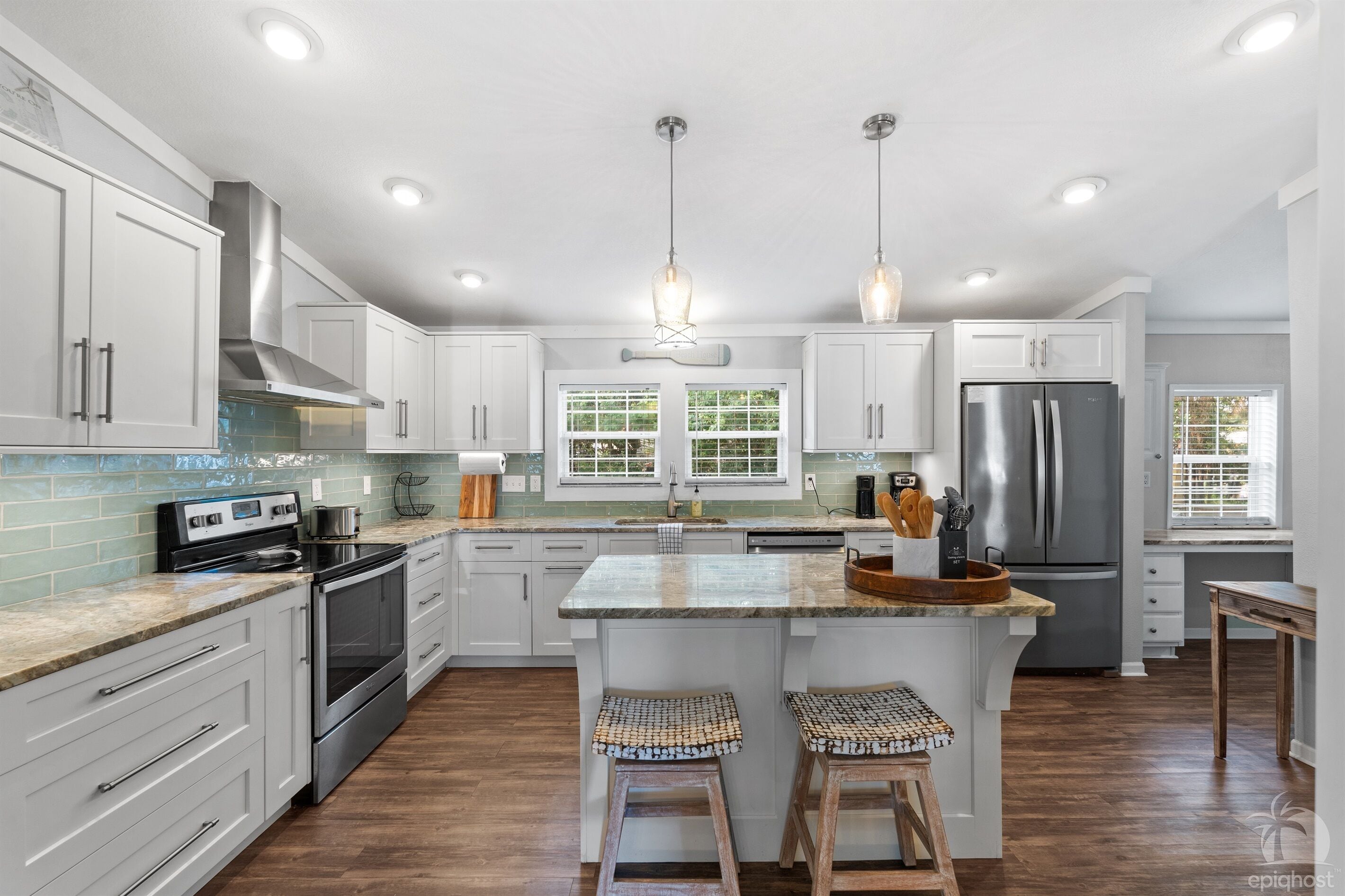 A modern kitchen with white cabinets, stainless steel appliances, and a central island with stools.