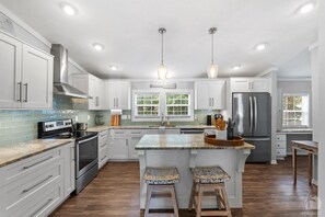 A modern kitchen with white cabinets, stainless steel appliances, and a central island with stools.