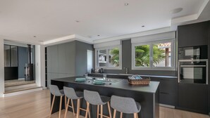 Una cucina moderna con isola centrale, sgabelli da bar e vista sull'esterno.