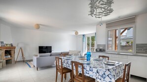 Ein modernes Wohnzimmer mit Essbereich, einem Flachbildfernseher und einer durchgehenden Tür erkennbaren Küche.