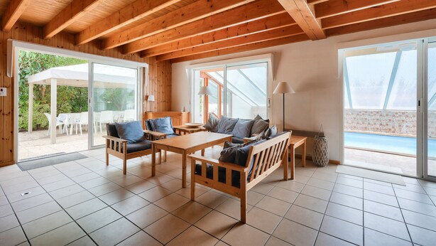 A spacious room with wooden beams, a large sliding glass door leading to an outdoor area, and a view of the sea. - 600 m from the sea, house for 8 adults / 2 children (La Faute-sur-Mer)
