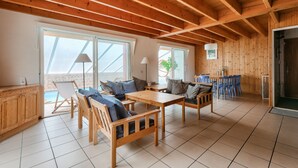A spacious room with wooden beams, a dining area, and large windows. - 600 m from the sea, house for 8 adults / 2 children (La Faute-sur-Mer)
