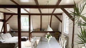 A cozy attic room with a dining table, chairs, and a plant.