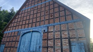 A traditional brick building with a steeply pitched roof and a large, blue wooden door.