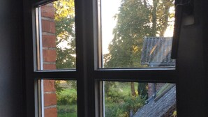 A window with a view of a brick wall and a garden.