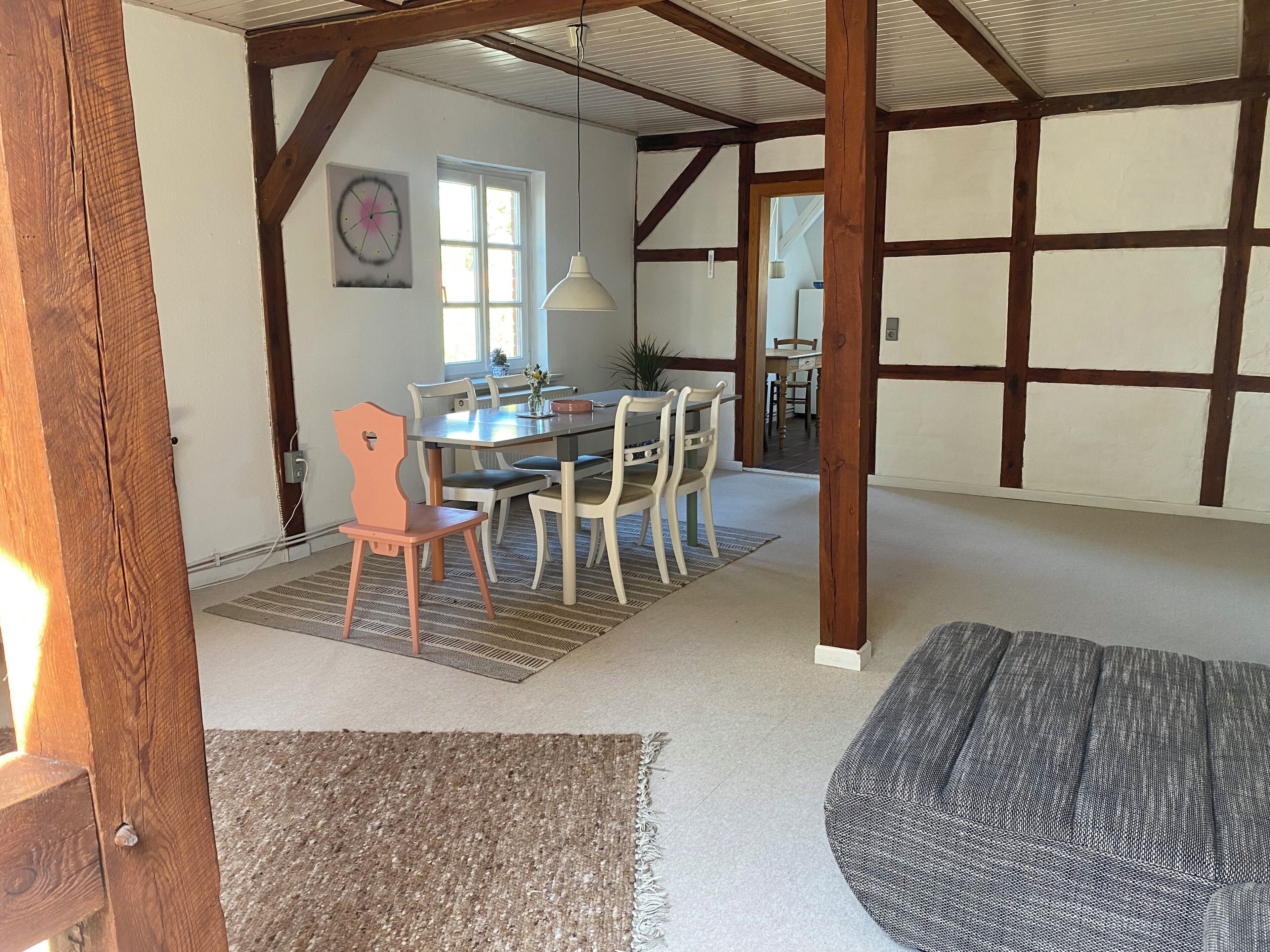Un espace repas comprenant une table et des chaises, un luminaire suspendu et une vue sur une autre pièce.