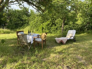 An outdoor dining area with a table set for two, surrounded by lush greenery and trees. - Stylish and bright apartment in a listed half-timbered house with a large garden (Lüchow)