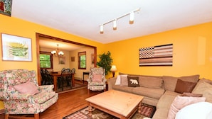 A living room with a wooden floor, a floral armchair, a sofa, and a coffee table.