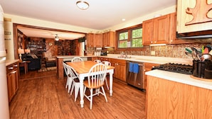 A kitchen with wooden cabinets, a dining table with chairs, a stove, and a sink.