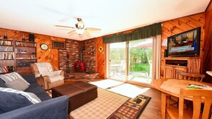 A cozy living room with a fireplace, a television, and a bookshelf.