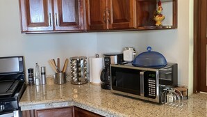 Una cocina con armarios de madera, microondas, cafetera y estufa.