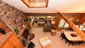 A cozy interior with a stone fireplace, wooden furniture, and a view of the outside.