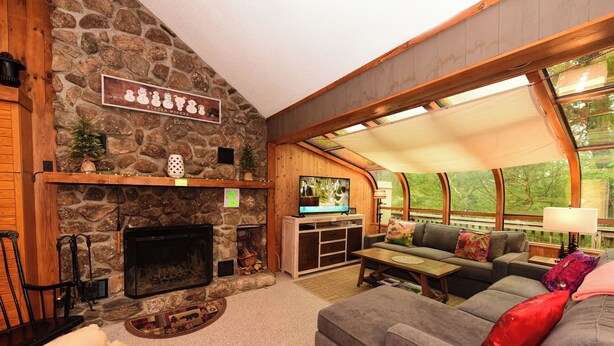 A cozy living room with a stone fireplace, a television, and comfortable seating.