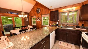 A kitchen with granite countertops, dark wooden cabinets, a clock, and a sign reading "Experts Only".