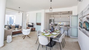 A modern living room with a dining area, kitchen, and a large window.