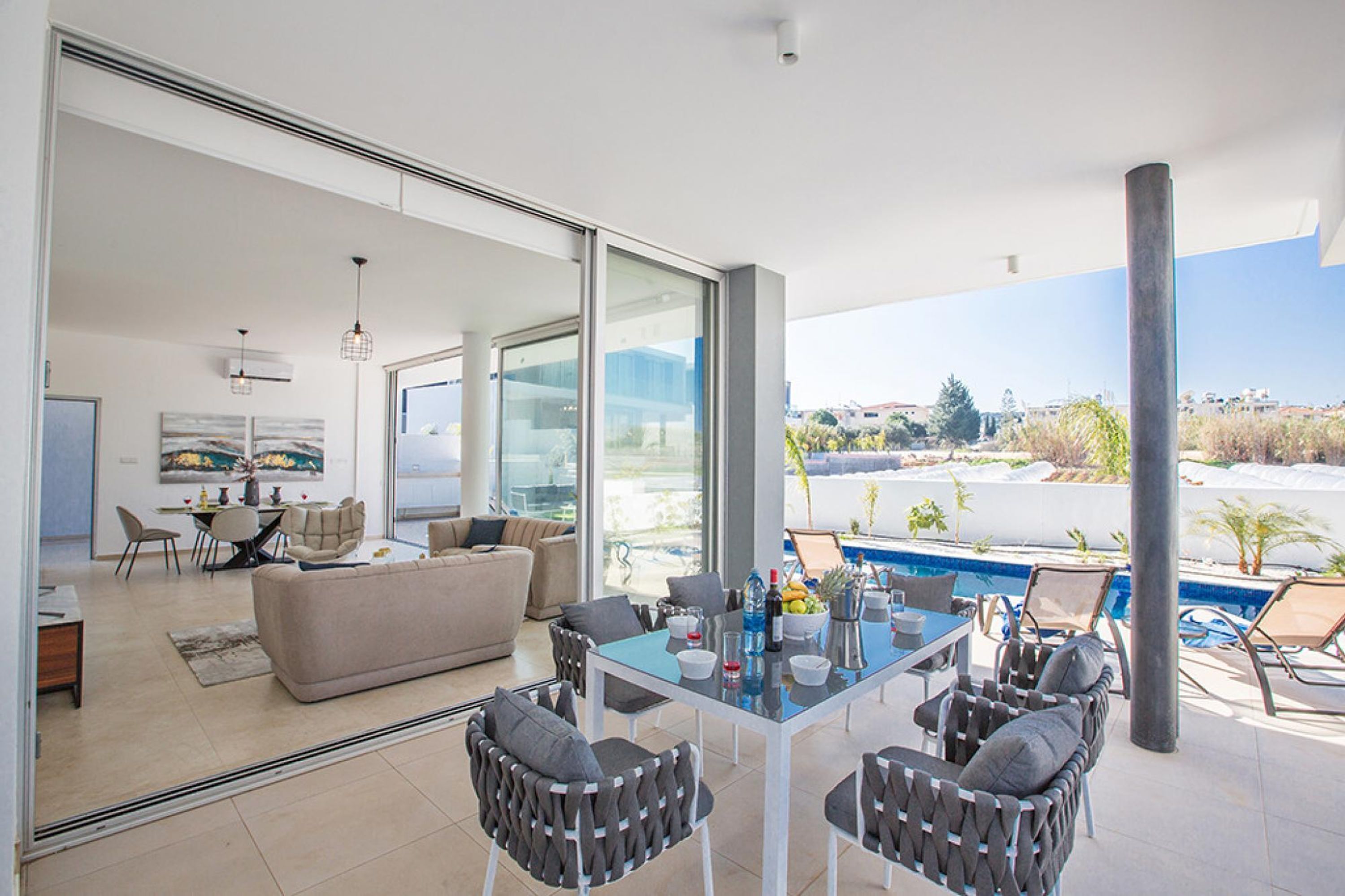 Sala moderna com mesa de jantar de vidro, assentos confortáveis e vista para uma piscina.