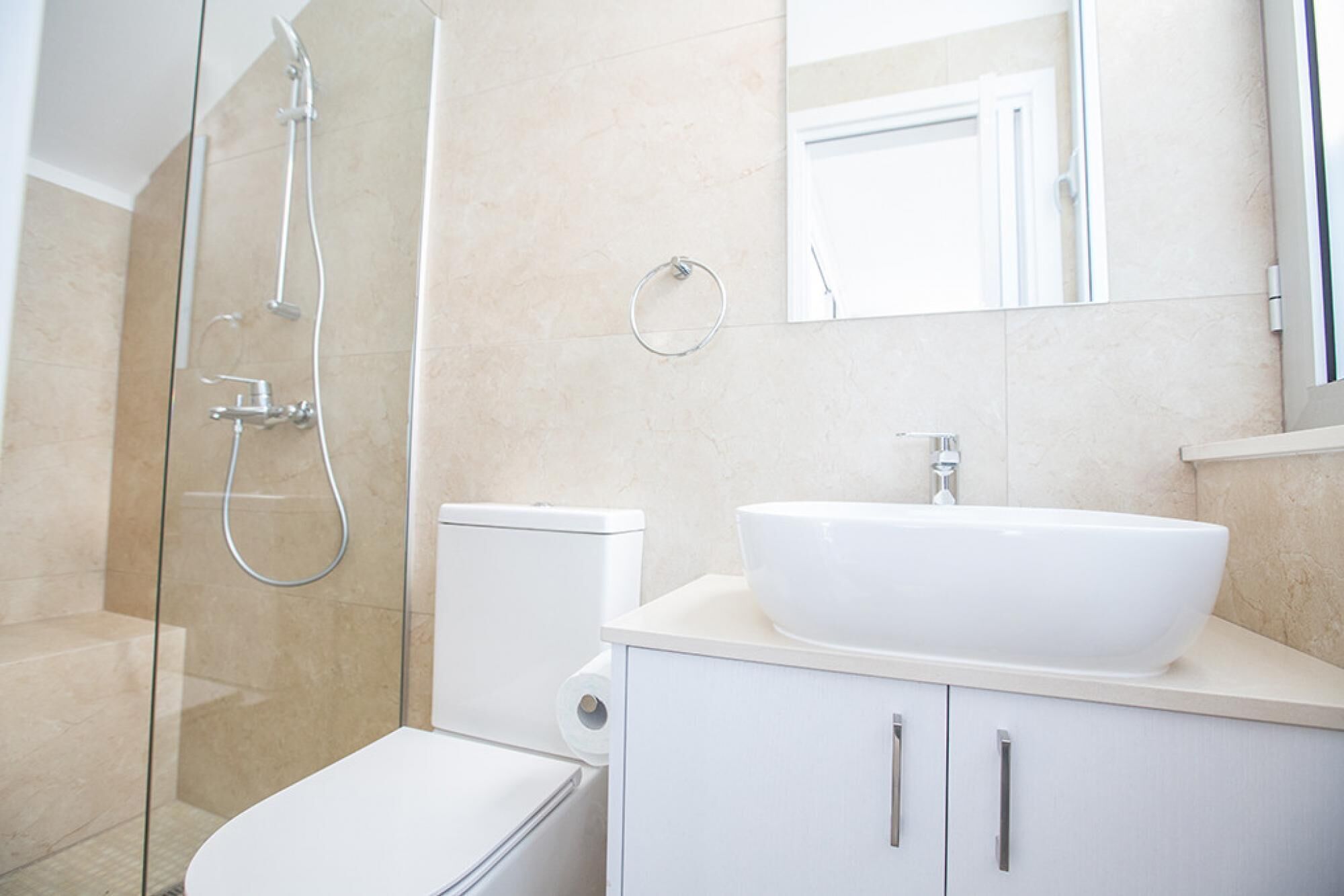 A modern bathroom with a glass-enclosed shower, a white sink, and a toilet.