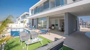 A modern house with a pool, outdoor seating, and a dining area.