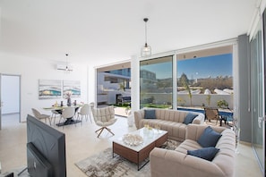 A modern living room with a television, sofa, coffee table, and dining area.