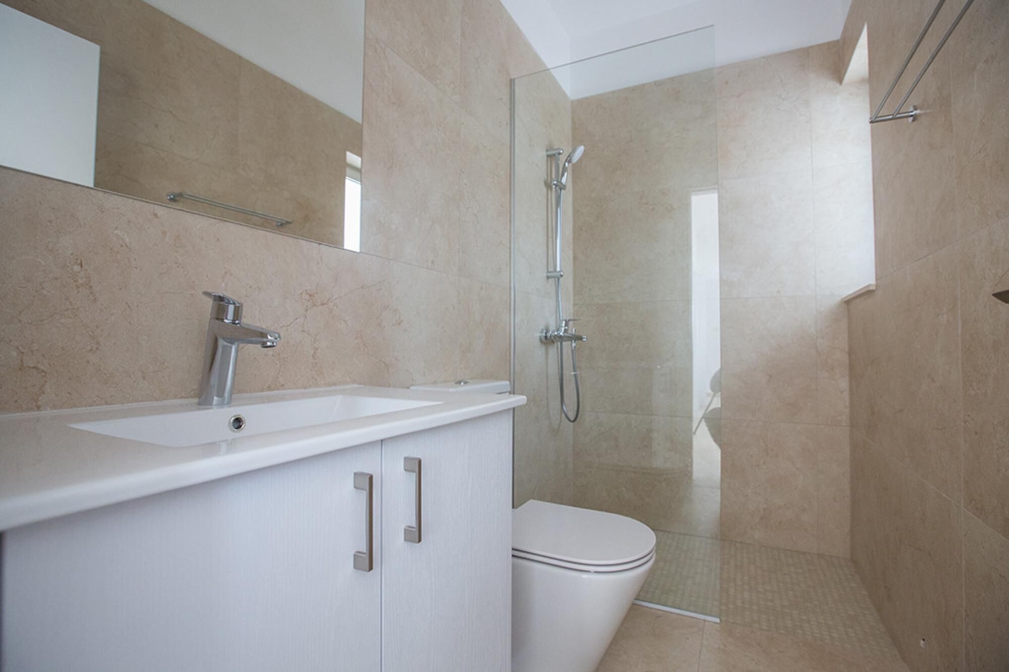 A modern bathroom with a white sink, mirror, and toilet.