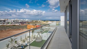 Un balcón con vistas a una obra en construcción, cielo despejado y costa lejana.