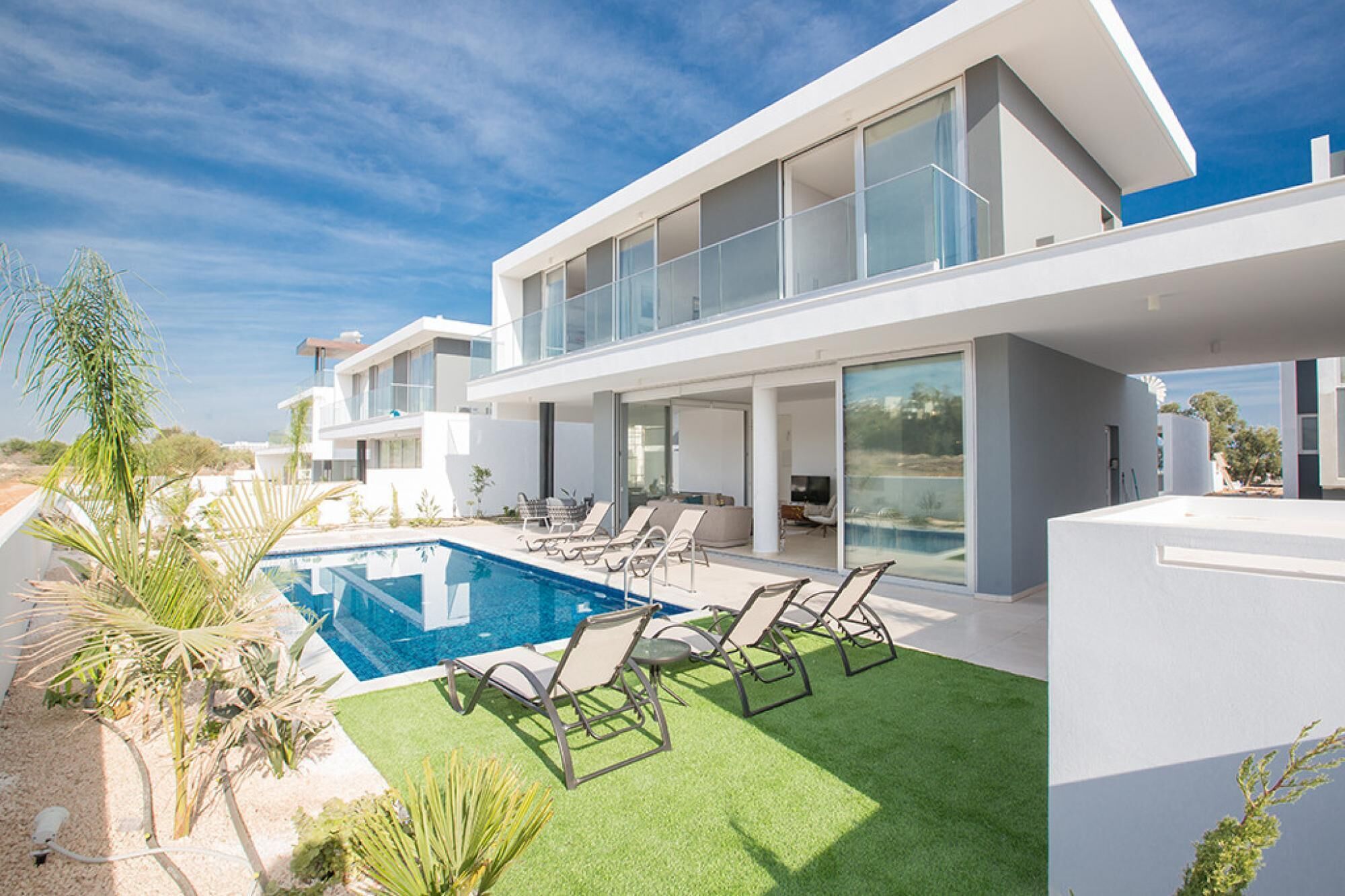 A modern house with a swimming pool, outdoor seating, and a view of the sea.