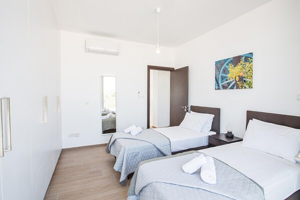 A hotel room with two beds, a large mirror, a painting, and a wooden floor.