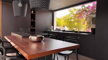 Een moderne keuken met een houten eettafel, zwarte stoelen en hanglampen.