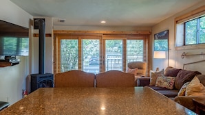 A cozy living room with a large granite table, a fireplace, and a comfortable sofa with cushions. - Alpine Villa Condo 1- Find a Perch in Ketchum at Treehouse Condo (Ketchum)