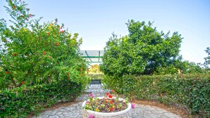 A stone pathway leading to a circular flower bed with a bench in the background. - Andelica Holiday Villa (Zakynthos)